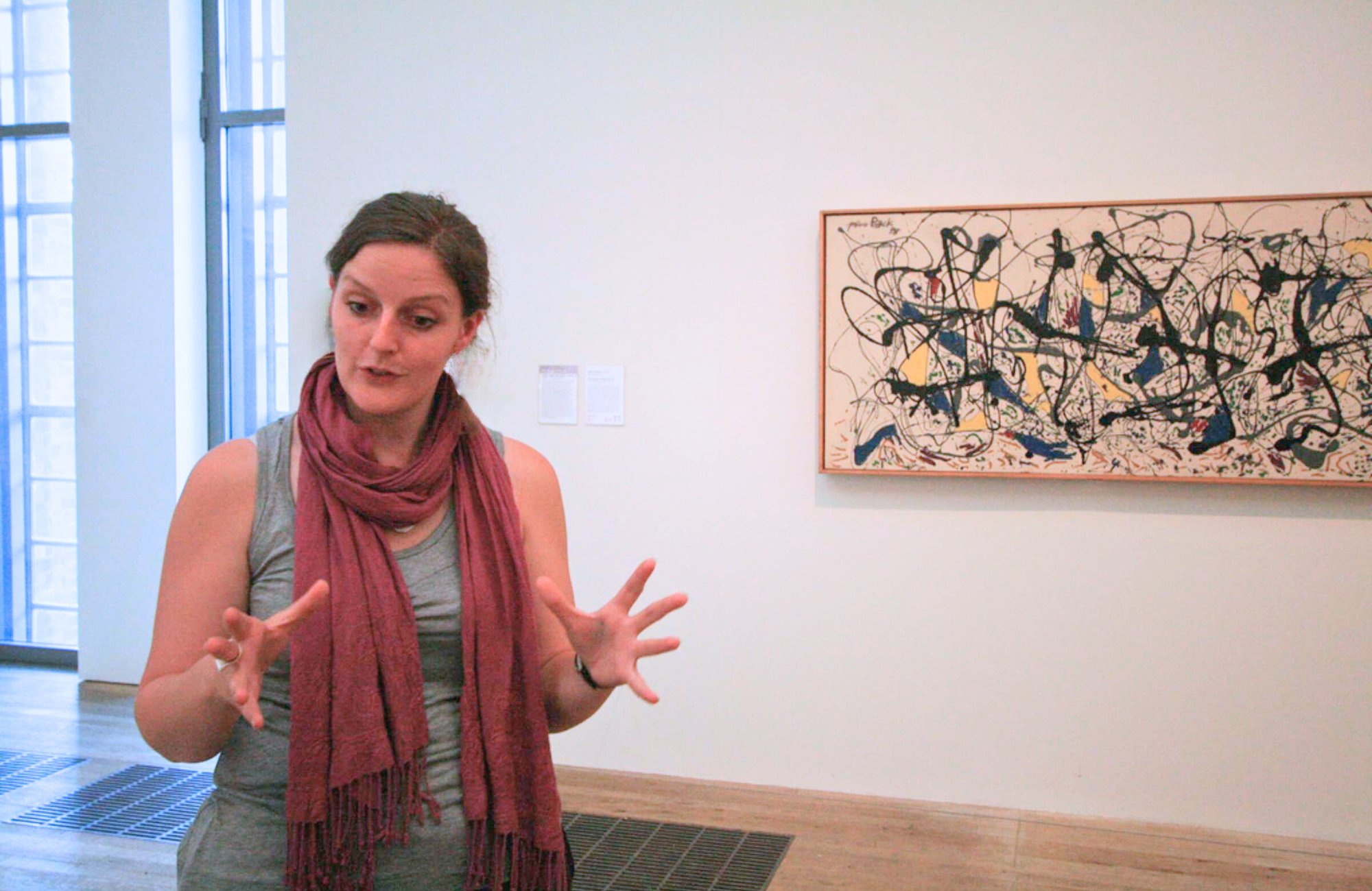 Art guide passionately explaining a Jackson Pollock painting to visitors inside Tate Modern.